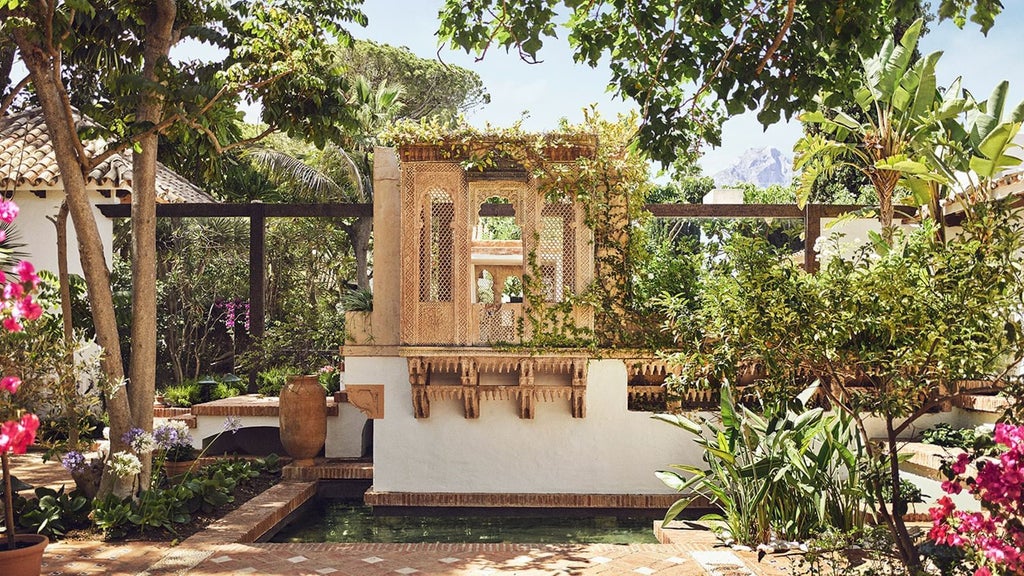 Luxurious white-washed Mediterranean resort with palm trees, azure pool, and golden sunlight overlooking the sparkling coastline of southern Spain