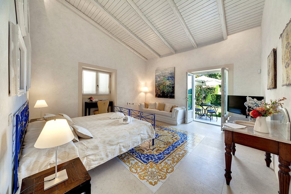 Elegant boutique suite with soft sage green walls, antique wood furnishings, crisp white linens, and traditional Sicilian architectural details in warm natural light