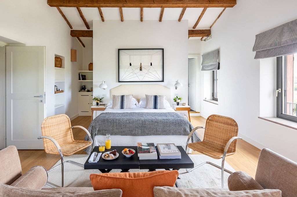 Elegant rustic-chic junior suite at Locanda Rossa, featuring warm terracotta tones, plush bedding, and a panoramic Tuscan countryside view through large windows.