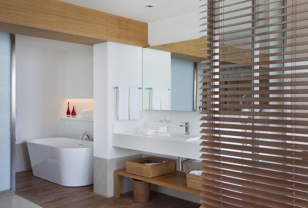 Luxurious modern suite at Janeiro Hotel with ocean-facing panoramic windows, sleek minimalist design, and Brazilian coastal elegance in soft neutral tones