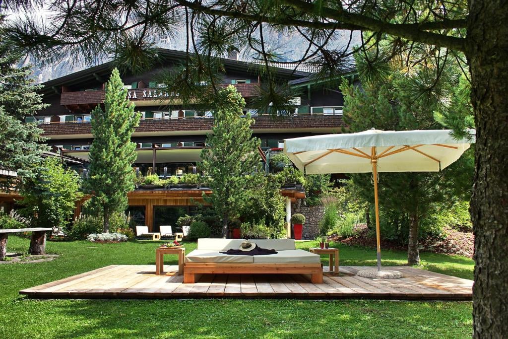 Elegant mountain hotel with stone and wood facade nestled in Italian Alps, featuring traditional Tyrolean architecture and snow-covered peaks