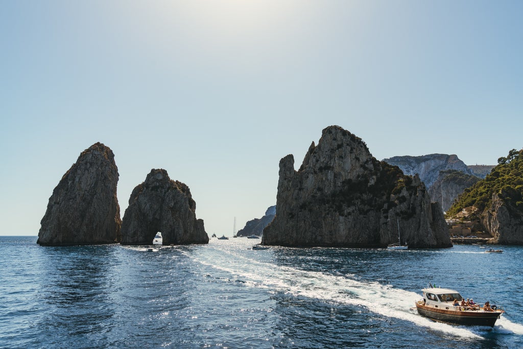 Sleek wooden yacht cruising along Amalfi Coast's dramatic cliffs, Mediterranean waters sparkling under golden sunlight, luxury deck visible