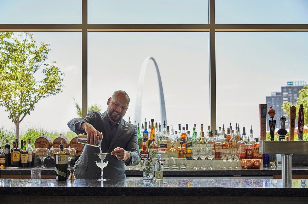 The luxury Four Seasons St. Louis hotel exterior with glass facade reflecting city lights, framed by modern architecture at twilight