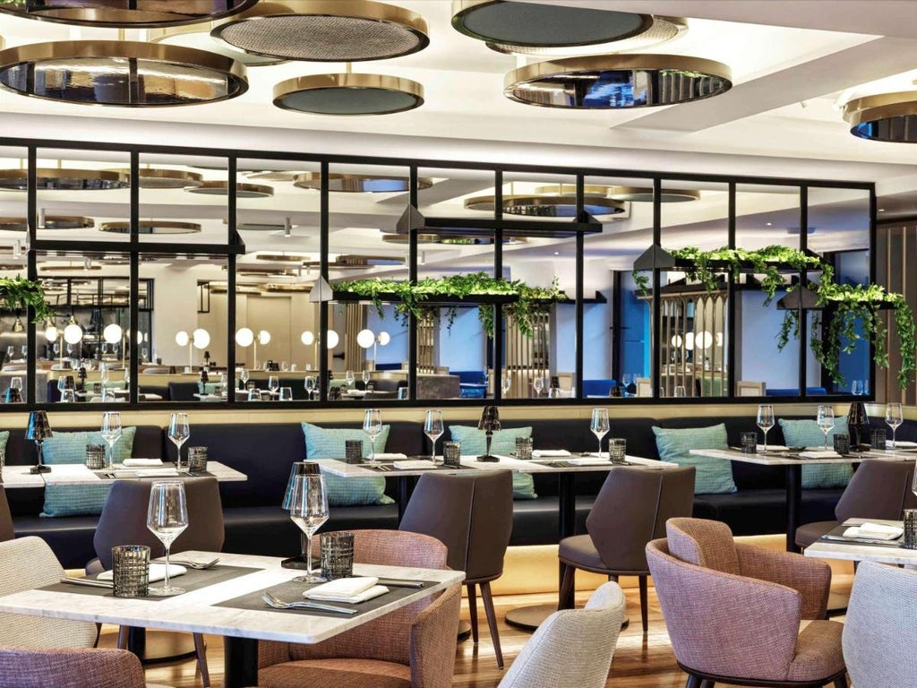 Elegant white marble entrance of Athens Capital Hotel with modern glass doors, brass accents, and chic outdoor lighting fixtures