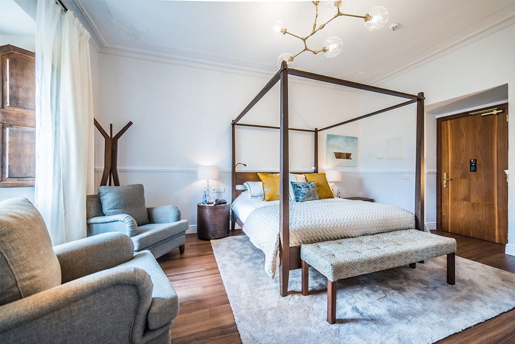 Elegant double room with garden view at L'Avenida Sóller, featuring soft linens, minimalist decor, and warm Mediterranean sunlight streaming through windows.