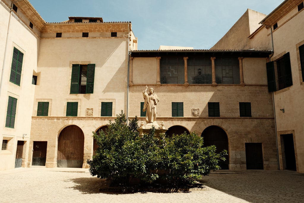 Historic Palma cobblestone streets with elegant architecture, sunlit limestone buildings, and picturesque Mediterranean urban landscape in Mallorca, Spain