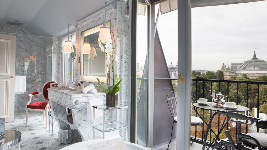 Luxurious Parisian hotel facade with elegant Haussmann-style architecture, ornate balconies, and pristine white exterior set against a soft blue sky.