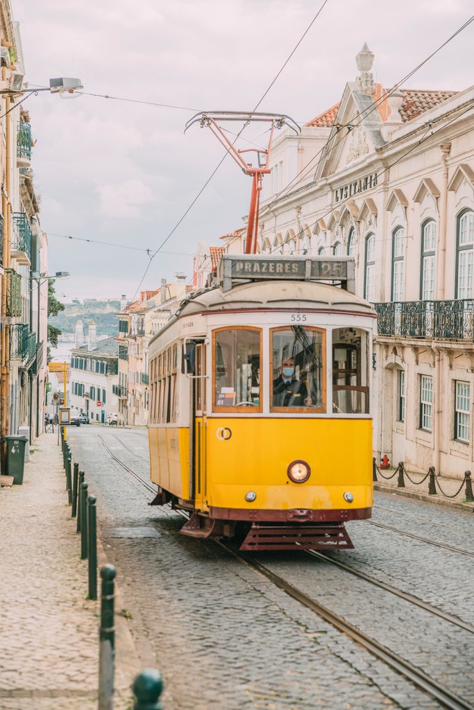 Sweeping coastal view of Lisbon's terracotta rooftops, historic trams and hillside architecture against the sparkling Tagus River at golden hour