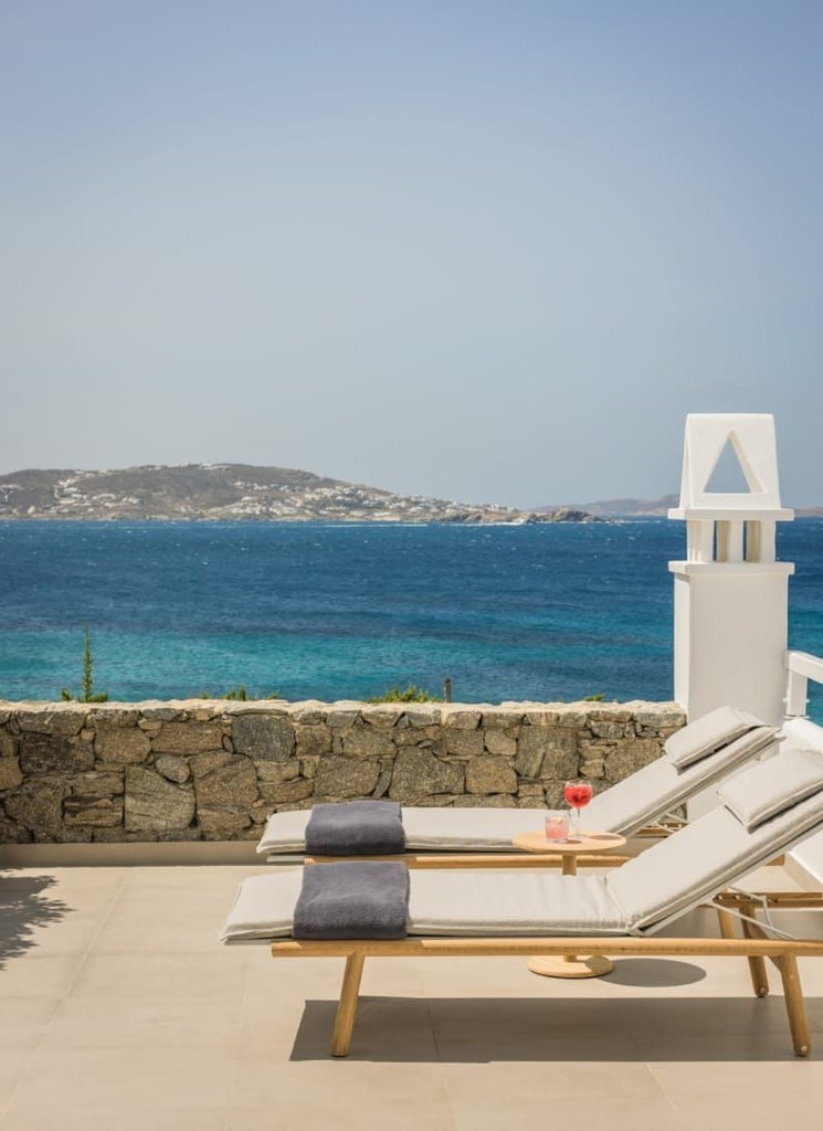 Luxurious junior suite at a scenic hotel in Mykonos, featuring a private plunge pool overlooking the Aegean Sea with elegant white and blue decor