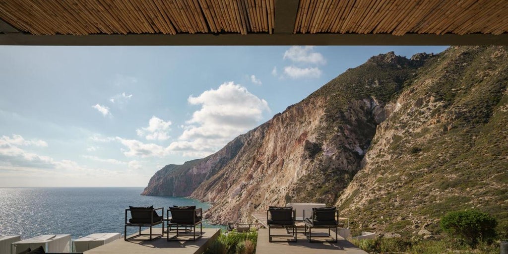 Contemporary infinity pool seamlessly merging with Aegean Sea views, featuring minimalist stone architecture and luxurious sunbeds at Milos Cove