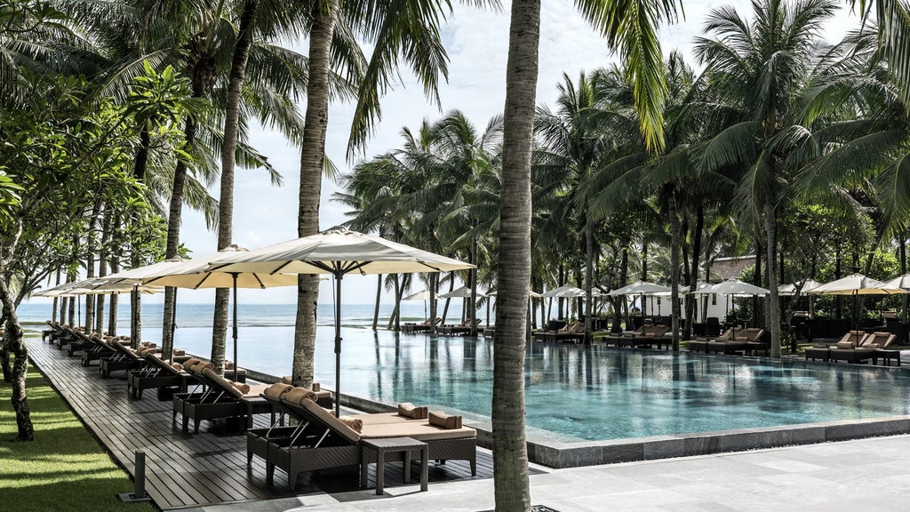 Luxurious beachfront villa at Four Seasons Nam Hai with infinity pool overlooking pristine South China Sea at golden sunset hour.