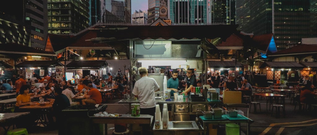 Street food vendors preparing traditional Singaporean snacks at a bustling hawker center, showcasing vibrant culinary heritage and local cooking techniques