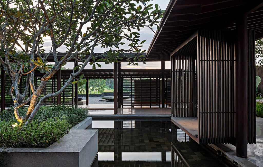 Multi-level infinity pool overlooking black sand beach and ocean, with modern minimalist architecture and tropical landscaping at dusk