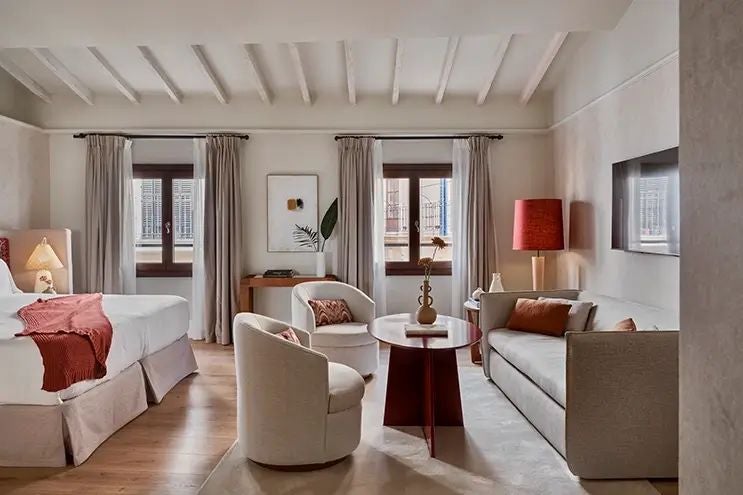 Luxurious stone-walled suite with antique wooden furnishings, elegant canopy bed, and ornate Spanish colonial decor in Mallorca's historic Posada Terra Santa