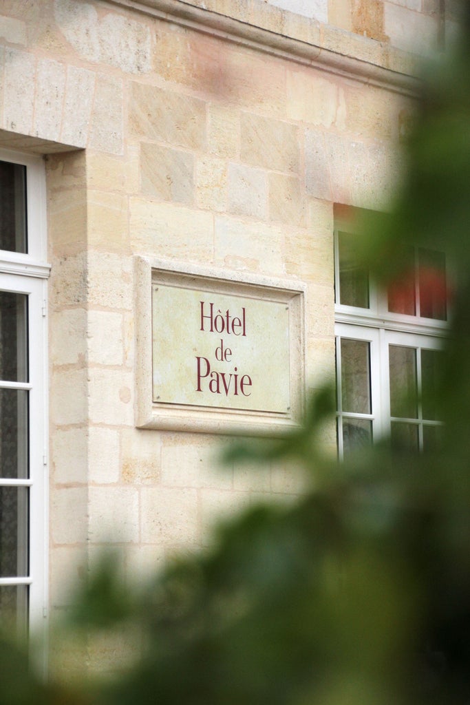 Historic Hotel de Pavie in Saint-Émilion, France features elegant stone architecture, arched windows, and climbing ivy on its facade