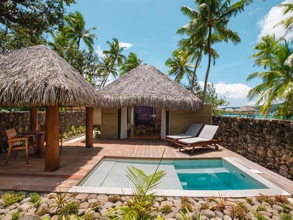 Luxurious overwater villa with private deck, infinity pool overlooking turquoise lagoon and distant mountains in French Polynesia