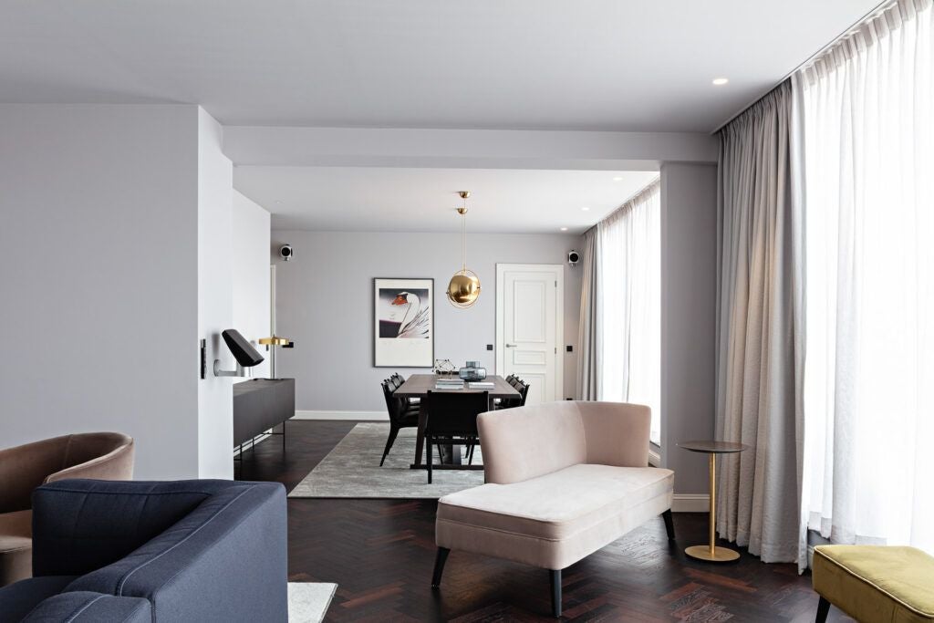 Elegant luxury hotel room with plush white bedding, contemporary furnishings, soft ambient lighting, and expansive windows in a Belgian boutique setting