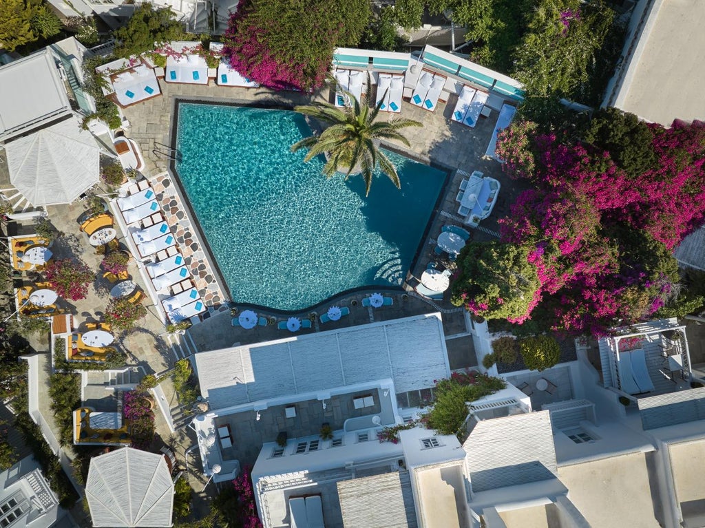 Luxurious white Greek hotel with infinity pool overlooking the Aegean Sea, featuring classic Cycladic architecture and stone terraces