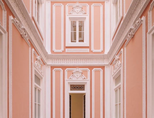 Ornate white palace-style hotel with grand classical architecture, marble columns and manicured gardens overlooking the Portuguese coast