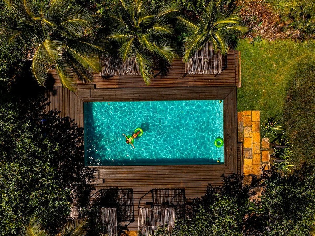 Luxurious rustic boutique hotel nestled in Brazilian countryside, stone facade with wooden accents, surrounded by lush tropical vegetation and elegant landscaping