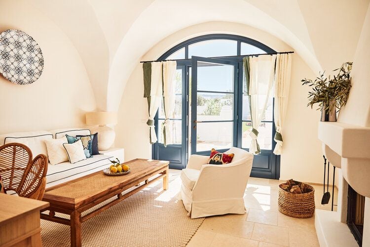 Rustic-chic stable suite at Masseria Calderisi, featuring exposed stone walls, elegant rustic furnishings, and soft natural light in a serene Italian countryside setting.