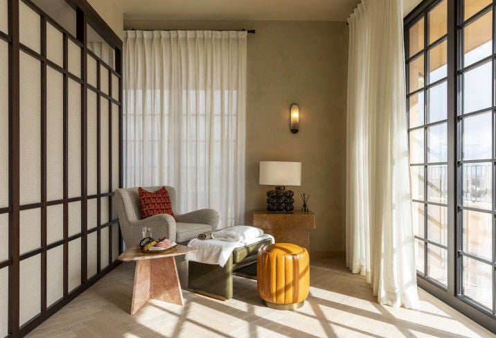 Elegant Italian courtyard at SoHo House Rome with ornate stone fountain, lush greenery, and vintage-style terracotta seating under arched colonnade