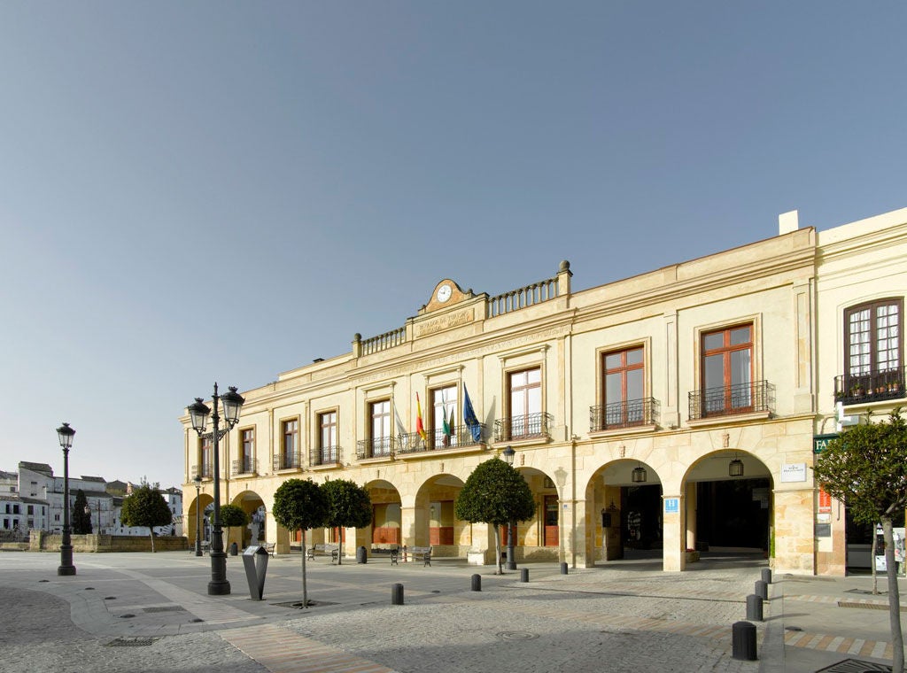 Historic Spanish parador hotel with stone facade, elegant archways, and manicured gardens set against mountainous backdrop at sunset