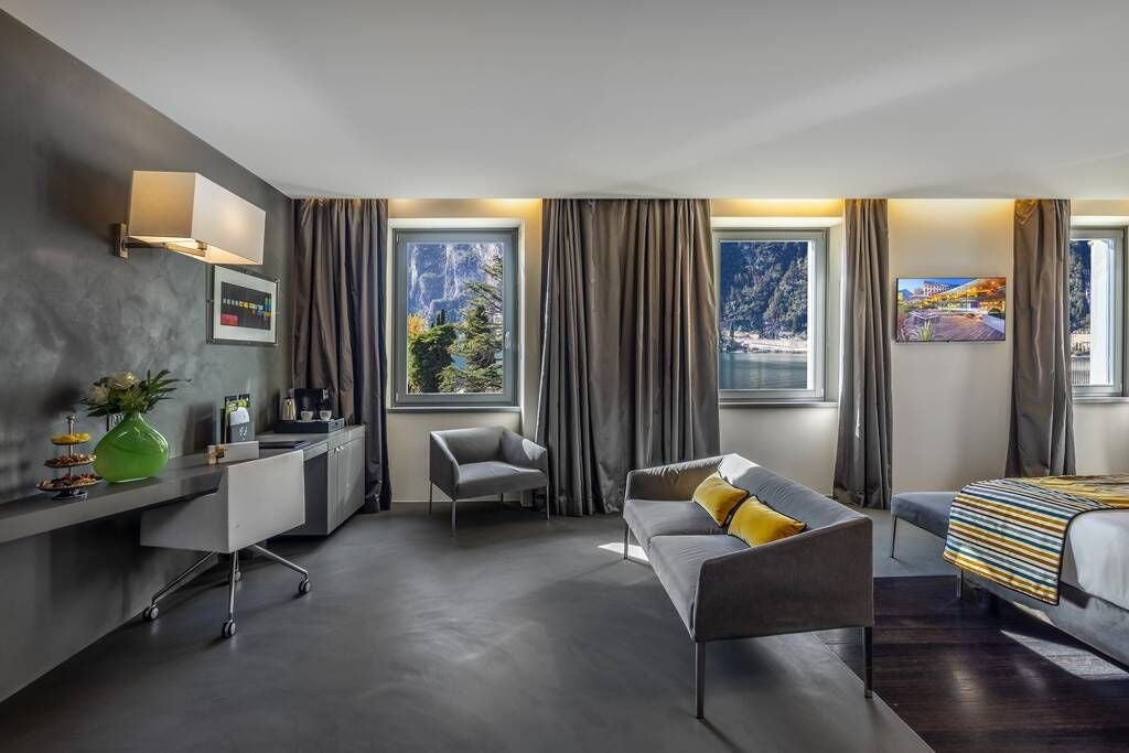 Elegant Italian luxury junior suite with panoramic lake view, featuring plush king bed, marble bathroom, and expansive windows showcasing scenic mountain landscape