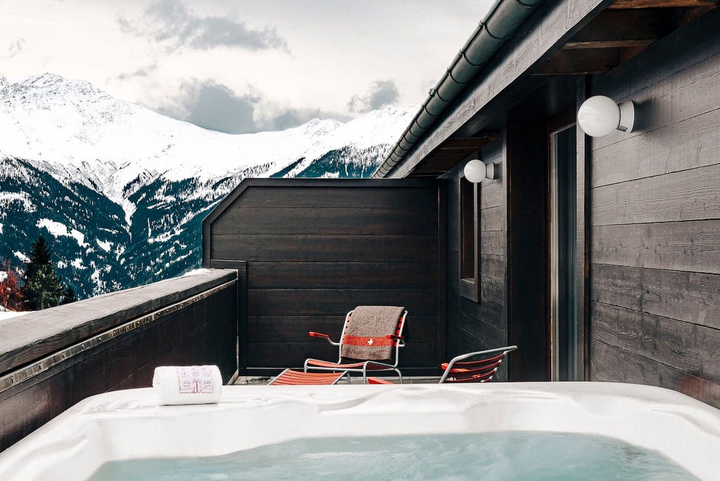 Luxurious modern alpine chalet nestled in Swiss mountains, featuring sleek wood paneling, panoramic windows, and minimalist design with breathtaking snow-capped landscape view