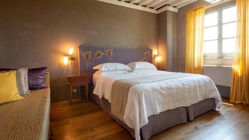 Elegant rustic-chic bedroom with soft neutral tones, plush white bedding, wooden floors, and vintage Italian countryside decor at Locanda al Colle