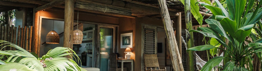 Luxurious wooden bungalow with tropical thatched roof, elegant white linens, and rustic Brazilian coastal charm in Trancoso's serene Pousada Capim Santo