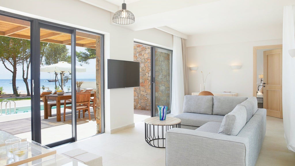 Elegant beachfront suite at seaside hotel with minimalist white decor, panoramic sea view, and private balcony overlooking turquoise Aegean waters in Skiathos, Greece