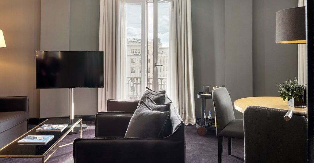 Elegant two-bedroom suite at luxury hotel with modern Spanish decor, plush king beds, city view, warm neutral tones, and sophisticated contemporary design