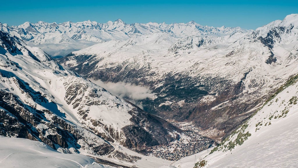 Luxury alpine hotel nestled in Swiss mountains, featuring elegant wood and stone exterior with snow-capped peaks and lush green landscape surrounding elegant chalet-style architecture