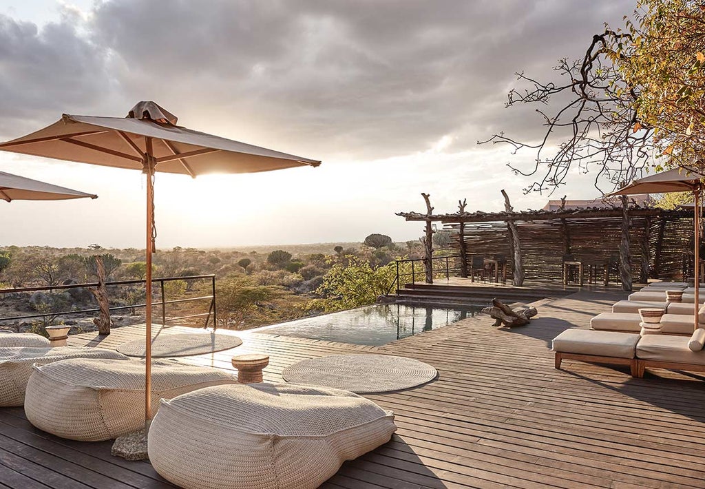 Luxurious safari lodge suite perched on rocky outcrop overlooking African savanna, featuring private deck and infinity pool at sunset