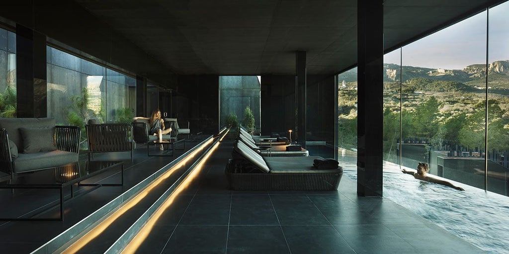 Modern, minimalist hotel suites suspended among pine trees in Spanish mountains, blending luxurious architecture with dramatic landscape design at sunset