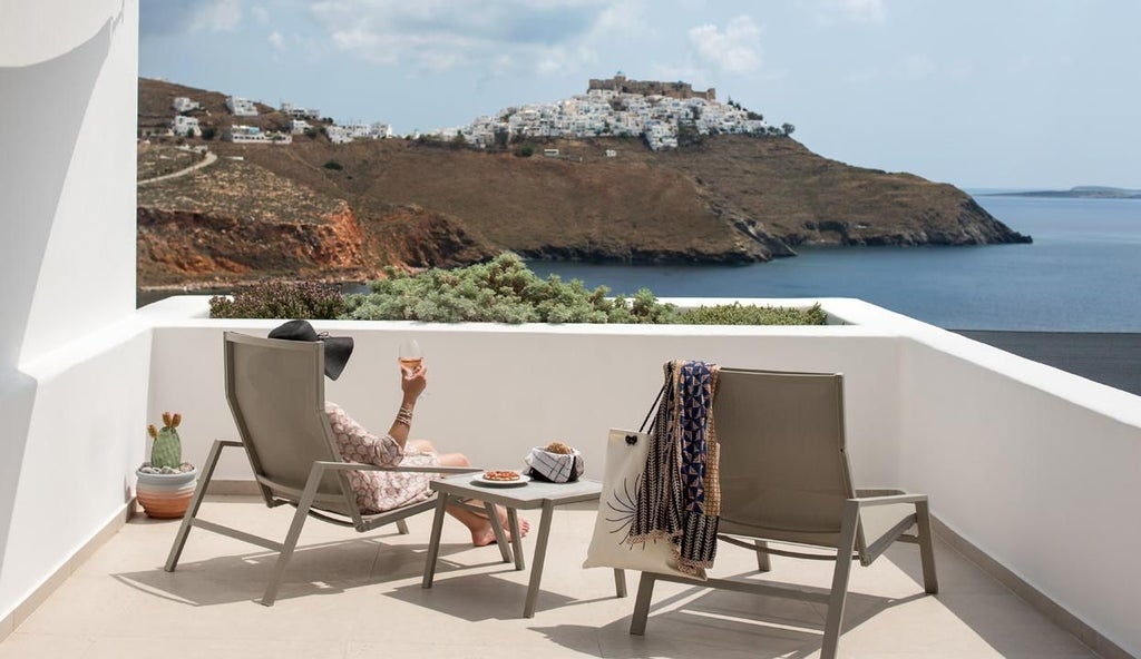 Luxurious white-washed Greek suite with blue accents, overlooking azure Aegean waters, traditional Cycladic architecture with elegant terrace and sea view