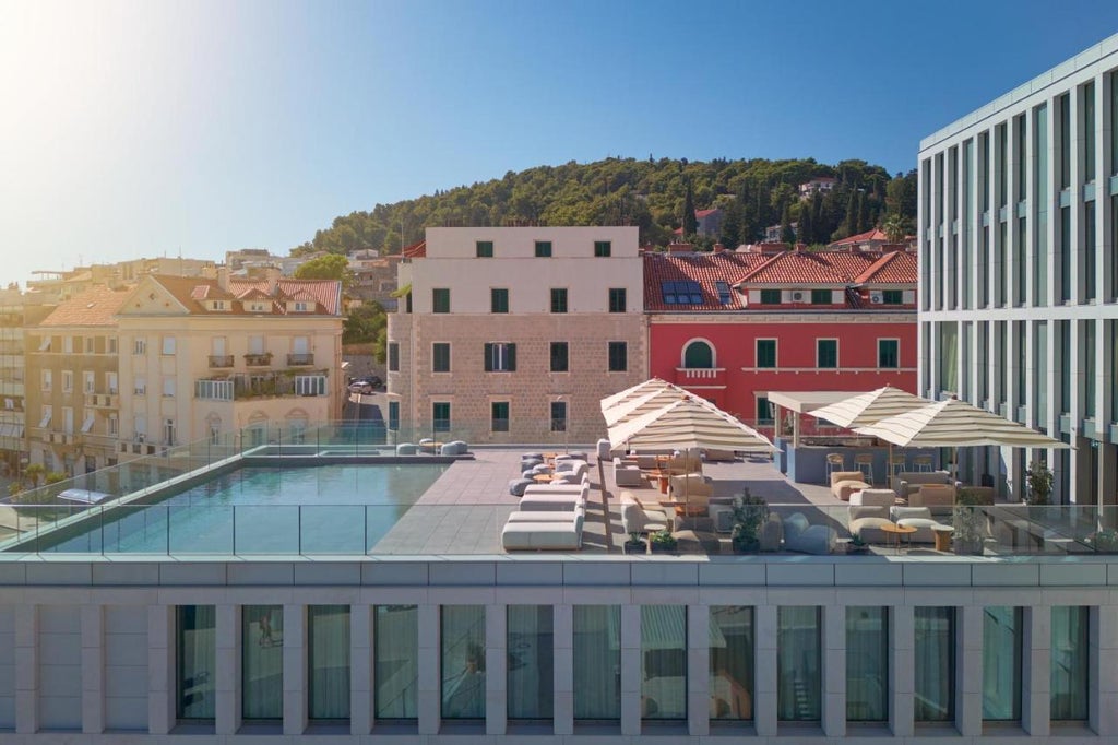 Elegant beige-facade Hotel Ambassador in Croatia with palm trees, glass balconies and Mediterranean architecture overlooking the sea