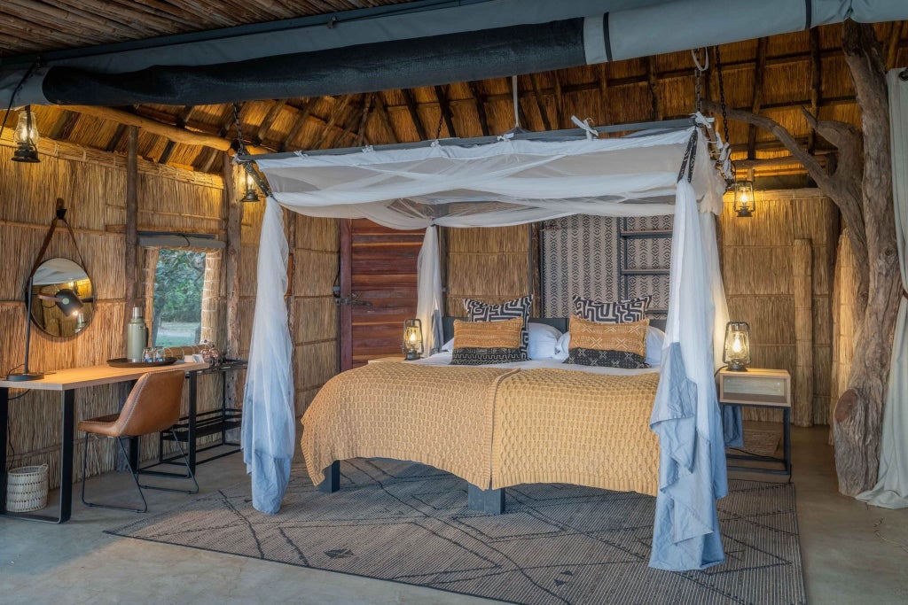 Elegant safari room with wooden accents, crisp white linens, and expansive views of Zambian wilderness through large canvas-draped windows at Time + Tide Kakuli.