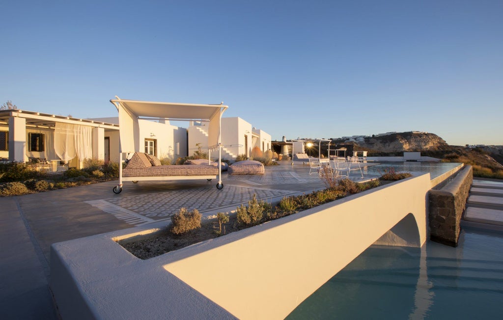 Minimalist white luxury suites with private infinity pools cascading down Santorini's cliffside, overlooking the Aegean Sea at sunset