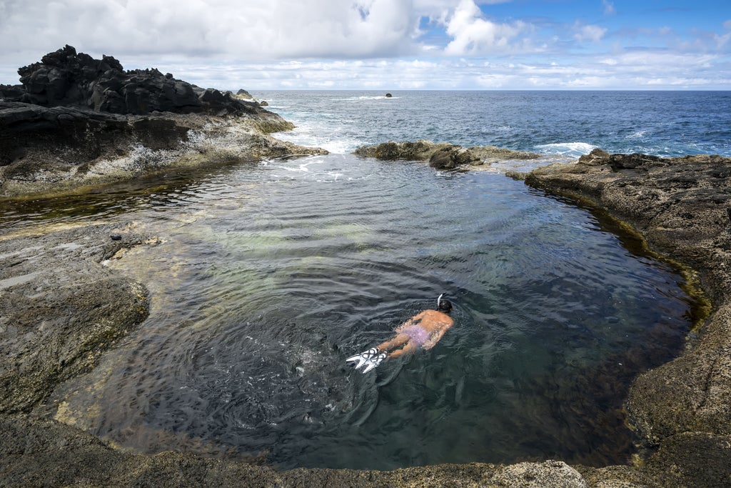 Steamy hot springs nestled in rugged Mosteiros landscape, with rocky terrain, thermal waters, and lush green vegetation against a dramatic Portuguese backdrop