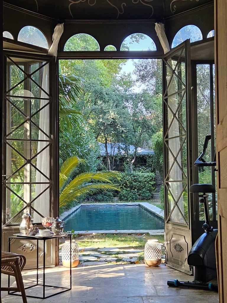 Elegant French boutique hotel facade with ornate architectural details, balconies with wrought-iron railings, and soft pastel exterior in historic scenset style