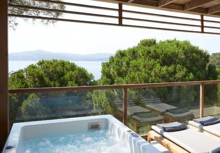 Modern luxury interconnected suite at ELIVI Skiathos hotel in Greece, featuring a private hot tub with sleek design and elegant white and blue color palette overlooking scenic view