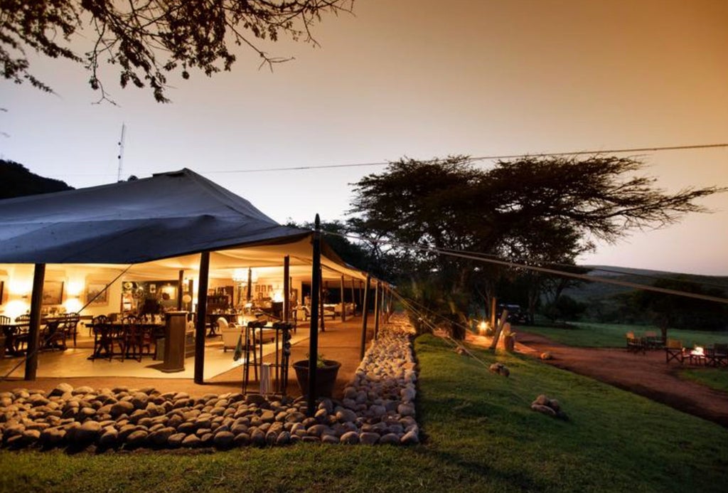 Private luxury safari tent with vintage colonial decor, canvas canopy, and antique furnishings overlooking the Kenyan savanna at sunset