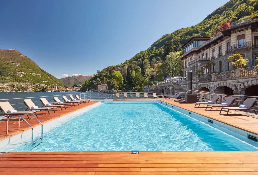 Elegant Mediterranean-style luxury hotel overlooking Lake Como, featuring cream facades, tiered terraces, and lush waterfront gardens