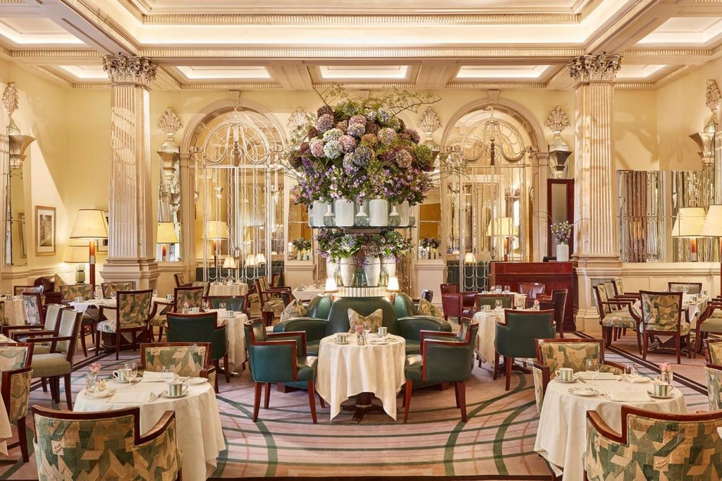 Art Deco entrance of Claridge's Hotel London with iconic revolving door, green awning and ornate stone facade lit by vintage lanterns.