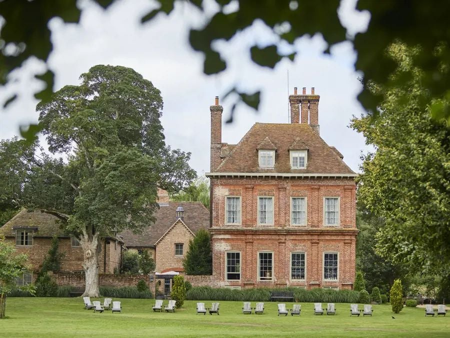 Rustic-chic farmhouse hotel with stone walls, lush gardens, and vintage decor, nestled in the verdant countryside near Bath, UK, exuding elegant countryside charm