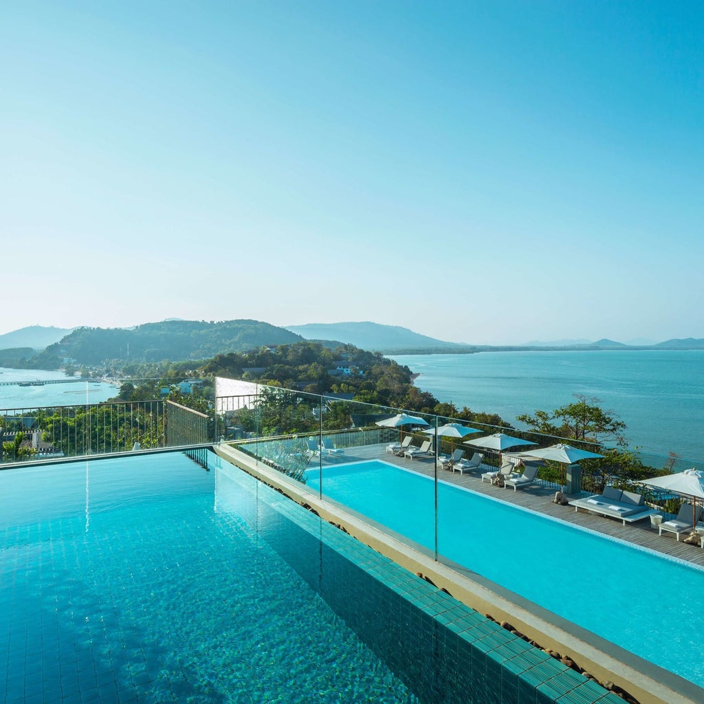 Luxurious seaside resort with sleek architectural design, infinity pool overlooking turquoise Andaman Sea, and minimalist Thai-inspired interiors in Phuket, Thailand