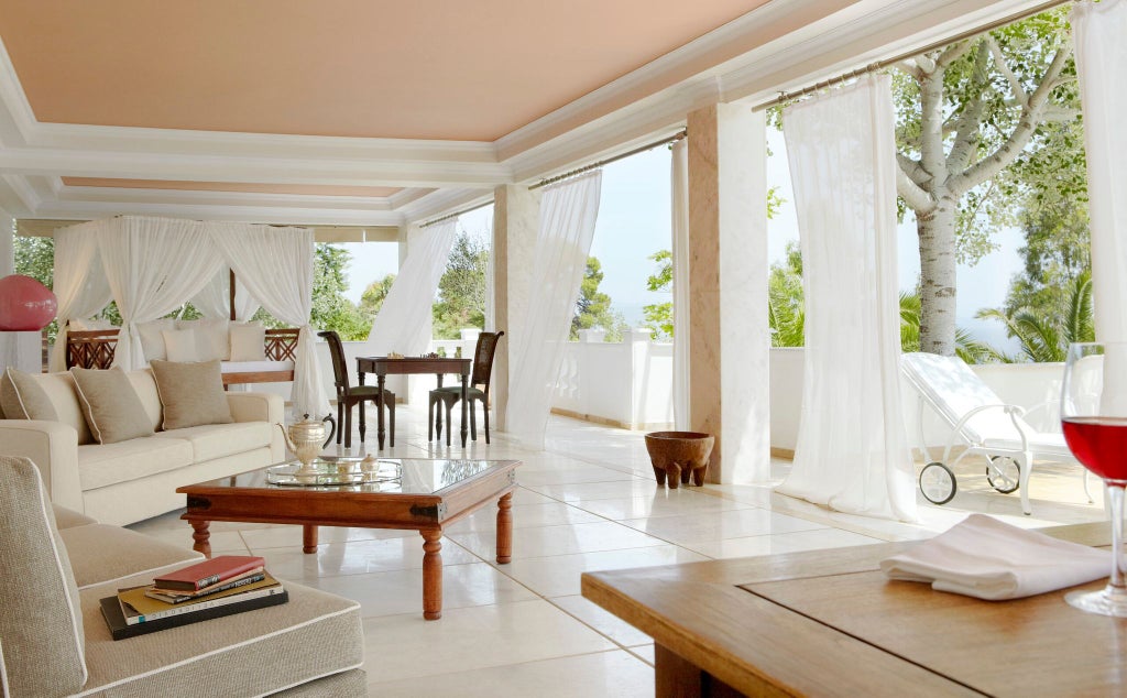 Luxurious white minimalist villa bedroom with panoramic Aegean Sea view, elegant wooden floors, and modern designer furnishings at beachfront resort