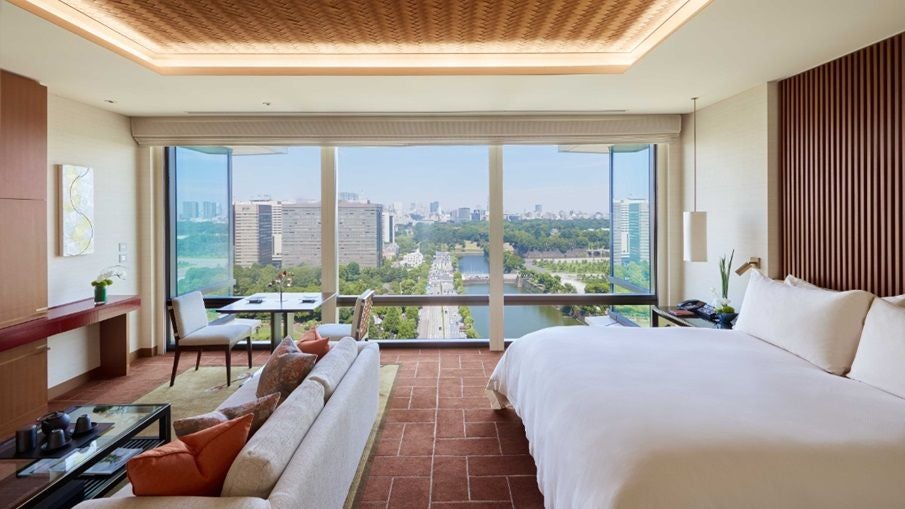 Elegant deluxe room at Peninsula Tokyo with city skyline view, contemporary Japanese design, plush king bed, and sleek marble bathroom with floor-to-ceiling windows